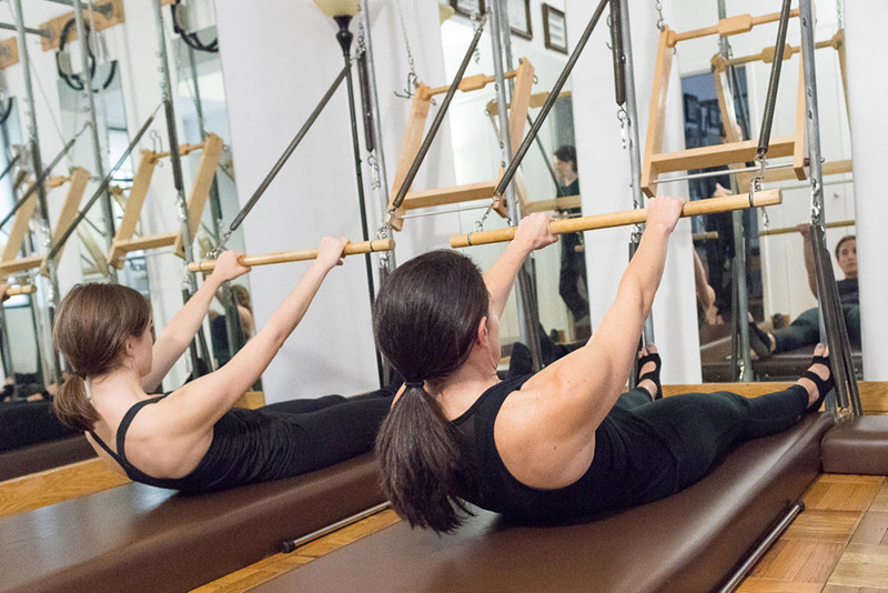 Healthy women are doing a classical Pilates duet workout at the Pilates Movement on E 68th Str NYC. 