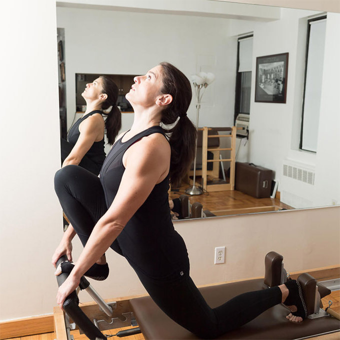 A woman working on the Reformer during her private session at The Pilates Movement studio, Manhattan location
