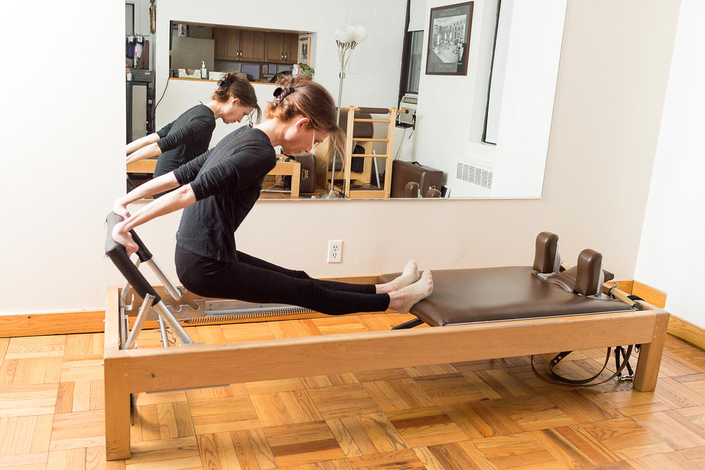 Woman performing exercises on the Cadillac during a private Pilates lesson in Upper East Side, NY